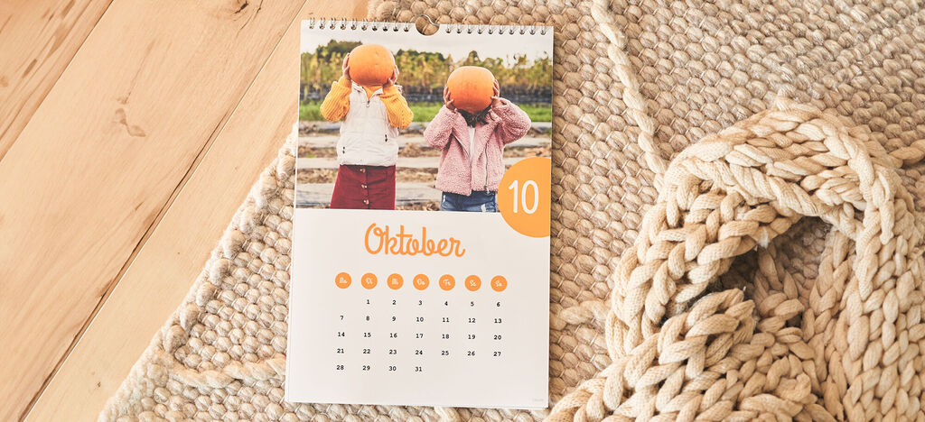 Twee kinderen met pompoenen op hun hoofd tonen een kalender voor oktober 10.
