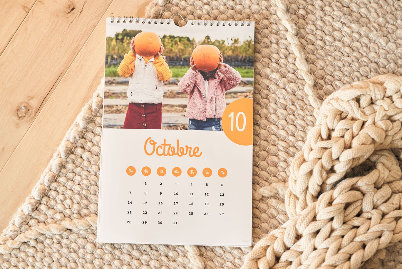 Deux enfants avec des citrouilles sur la tête près d’un calendrier d’octobre.